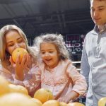 Family enjoying a cheerful shopping trip together at the grocery store, selecting fresh oranges.