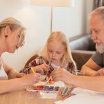 A family of three enjoying creative time with painting and drawing at home.